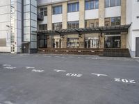 an empty building with signs on the street and people on bikes in traffic passing by