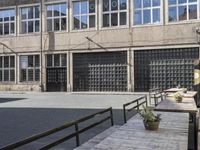 the side of an industrial building with a bench and stairs outside of it and a man that is walking