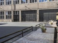 the side of an industrial building with a bench and stairs outside of it and a man that is walking