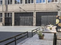 the side of an industrial building with a bench and stairs outside of it and a man that is walking