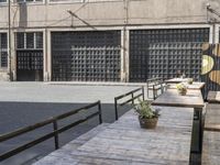 the side of an industrial building with a bench and stairs outside of it and a man that is walking