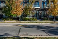 a fire hydrant on the side of a road near a building and sidewalk with trees