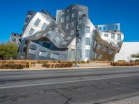 the building is clad in shiny silver tiles, it's located on a street corner