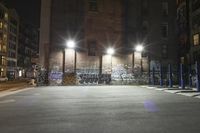 a building is covered in graffiti next to another building at night with lights and parking meters