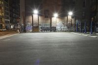 a building is covered in graffiti next to another building at night with lights and parking meters