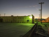 a building with graffiti on it sitting next to an empty road at night with the sky in the background