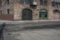 an empty street lined with a brick building and a small fire hydrant in front