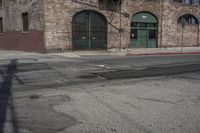 an empty street lined with a brick building and a small fire hydrant in front