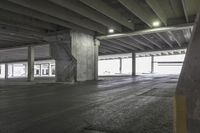 an empty, empty parking garage with concrete floors and large concrete pillars, next to stairs leading up