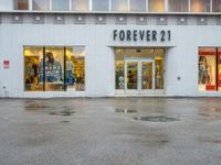 a store front with several small windows in an empty lot near a building with a sign for forever 21 on the window