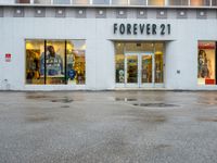 a store front with several small windows in an empty lot near a building with a sign for forever 21 on the window