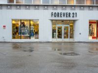 a store front with several small windows in an empty lot near a building with a sign for forever 21 on the window