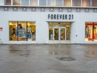 a store front with several small windows in an empty lot near a building with a sign for forever 21 on the window