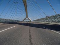 a truck driving across a bridge near a street corner near buildings and a bridge with many cables