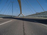 a truck driving across a bridge near a street corner near buildings and a bridge with many cables