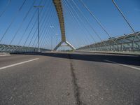 a truck driving across a bridge near a street corner near buildings and a bridge with many cables