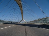 a truck driving across a bridge near a street corner near buildings and a bridge with many cables
