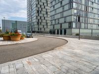 a road next to the building next to each other with potted plants on either side