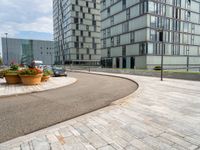 a road next to the building next to each other with potted plants on either side