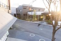 a couple of buildings with a tree and an umbrella outside of it in the sunlight