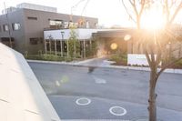 a couple of buildings with a tree and an umbrella outside of it in the sunlight