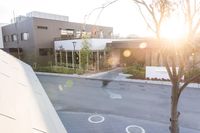 a couple of buildings with a tree and an umbrella outside of it in the sunlight