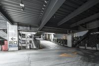 a parking garage with some stairs near it and a motorcycle in the distance on the road