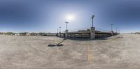 a view through a fish eye lens on an empty parking lot and street lights near a bridge