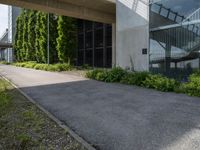 a building with glass walls is shown through the grass near the sidewalk and stairs to it