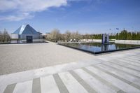 an outdoor pool with stairs leading to a building with a pyramid and a triangle shaped structure