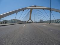 a truck driving across a bridge near a street corner near buildings and a bridge with many cables