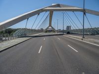 a truck driving across a bridge near a street corner near buildings and a bridge with many cables