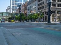 an empty street with buildings and parked cars on the sidewalks and green lanes on the sidewalk