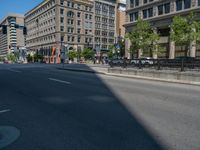 an empty street with buildings and parked cars on the sidewalks and green lanes on the sidewalk