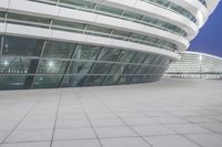 a man with a black backpack is looking down at something outside of a building near by