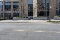 an empty street and building on the other side of it with some green bushes and bushes