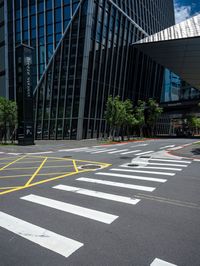 a street with cross walk lines at an intersection in the city, at a few buildings