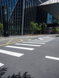 a street with cross walk lines at an intersection in the city, at a few buildings