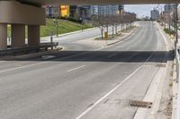 a empty roadway is surrounded by tall buildings and a sidewalk that runs down it with cars parked in the distance