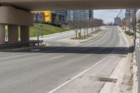 a empty roadway is surrounded by tall buildings and a sidewalk that runs down it with cars parked in the distance