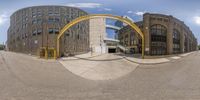 a panorama view of an exterior area with buildings and arches, including an arched entrance and the entrance of an empty building