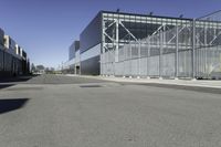 a parking lot with concrete floor and large glass building in the back ground on a clear day