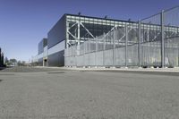 a parking lot with concrete floor and large glass building in the back ground on a clear day