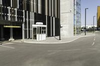 a bus stop at an empty street intersection near tall buildings on a bright, sunny day