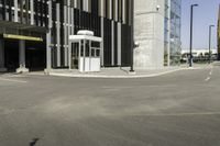 a bus stop at an empty street intersection near tall buildings on a bright, sunny day