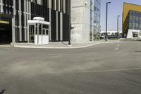 a bus stop at an empty street intersection near tall buildings on a bright, sunny day