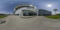 a 360 - view lens of an office building near a field and basketball hoop in the foreground