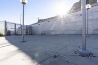 a cement parking garage with an opening on the left side of the parking space, with several concrete street lights and buildings in the background