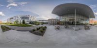 a fisheye image of the outside of a building with benches and picnic benches on the sidewalk