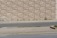 a man is riding a bike past the curb with some plants behind him, in front of the wall